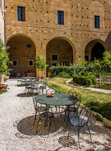 Immagine con sedie, archi, finestre, piante, verde, giardino, tavolini, erba, siepi, tavoli, panchina, panchine, portico, palazzo, ferro, vasi, ghiaia, aiuole, cortile, tavolo, mattoni, ombre
