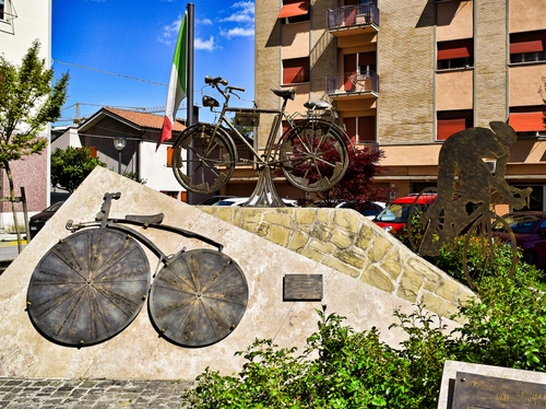 Immagine con bandiera, monumento, bicicletta, biciclette, finestre, case, ciclista, cerchi